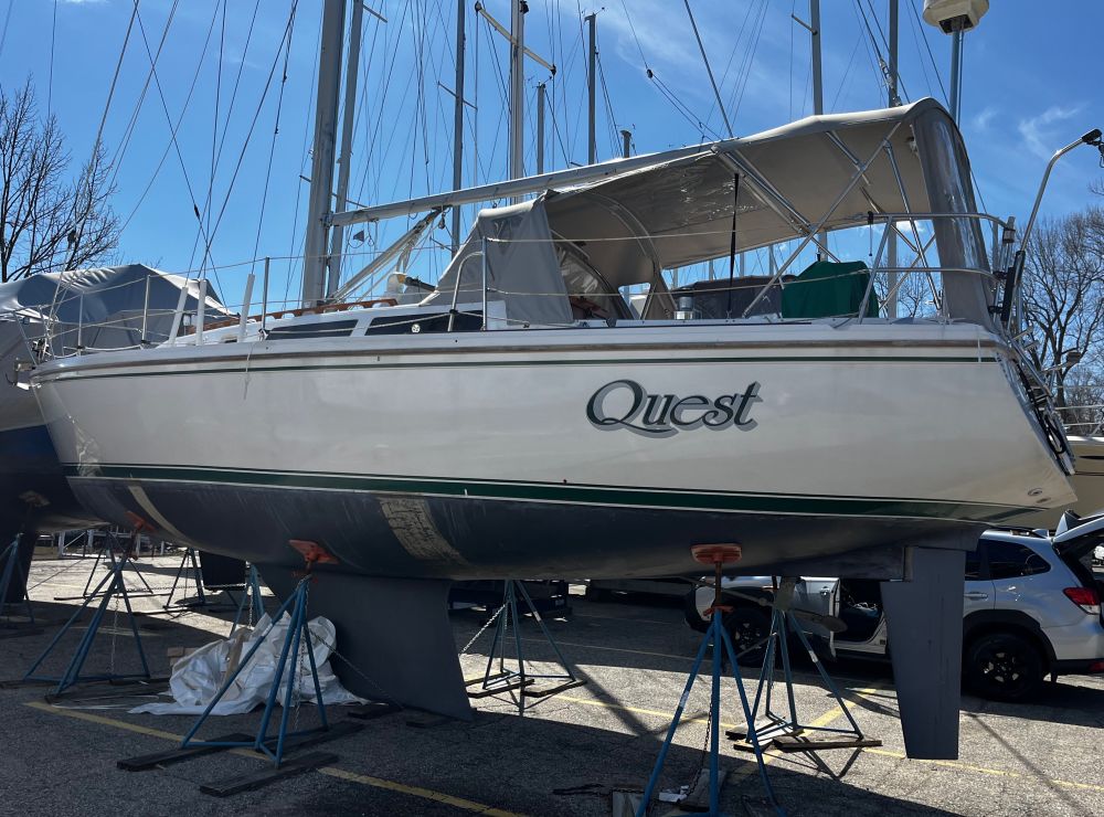 Picture of our 34 foot Catalina sailboat named quest sitting in a cradle in a marina parking lot, shiny with fresh wax and awaiting being launched for the summer