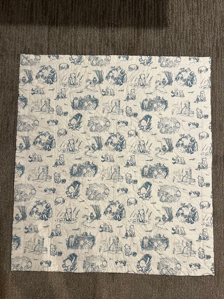 The backside of the finished baby quilt, using white fabric with light blue vintage Winnie the Pooh sketches