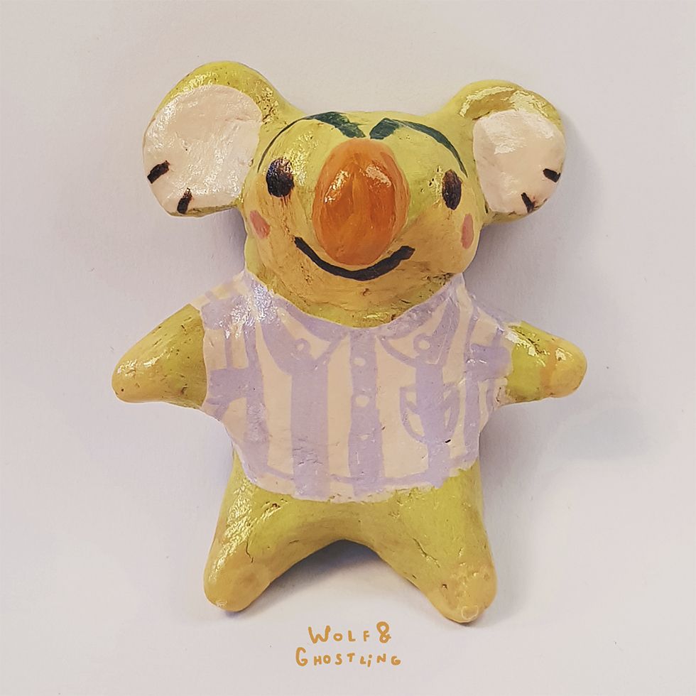 a little sculpture of animal crossing character lyman, who is a lime green koala with nose and eyebrows that look like a carrot