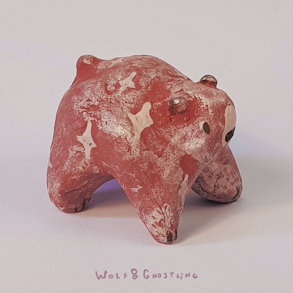 a small, round figurine of a pink bear with a frosted dusty appearance. stars are painted on her. she looks like a mochi ball