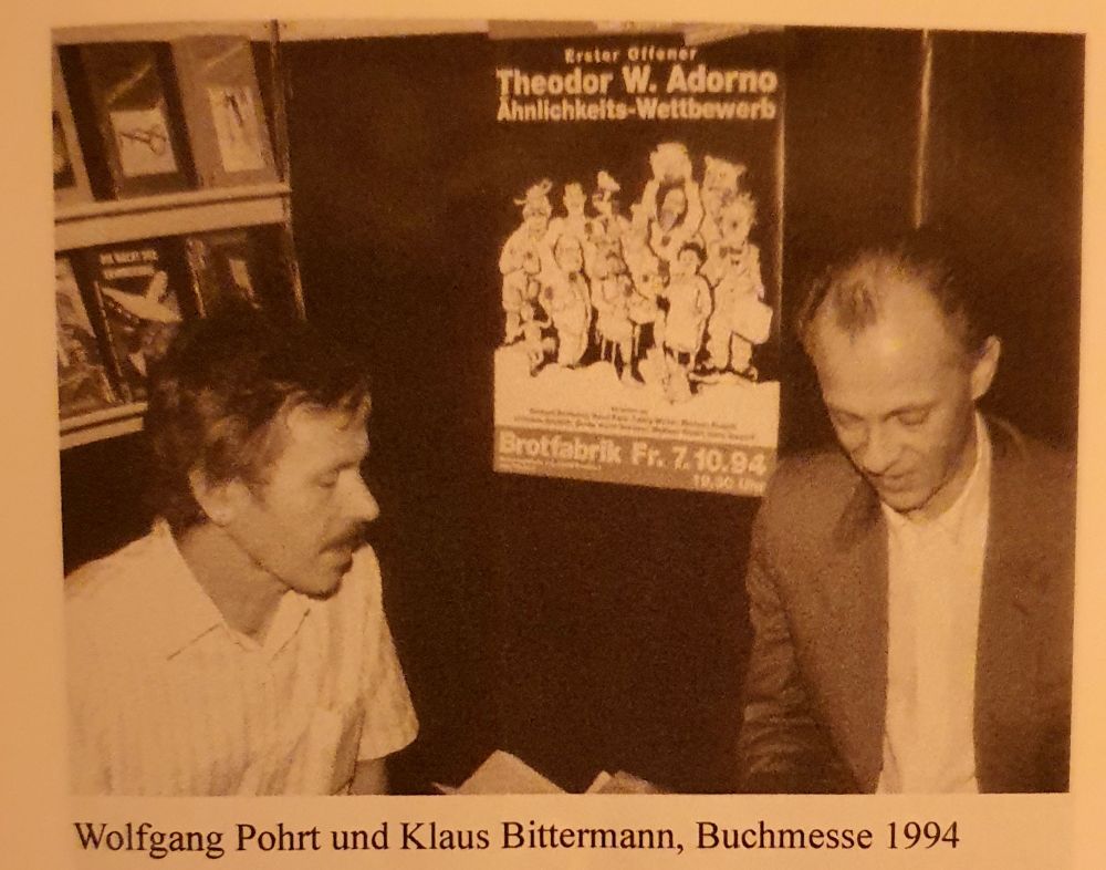 Wolfgang Pohrt und Klaus Bittermann, Buchmesse 1994. Hinter den beiden ein Plakat: Erster offener Theodor W. Adorno Ähnlichkeitswettbewerb.
