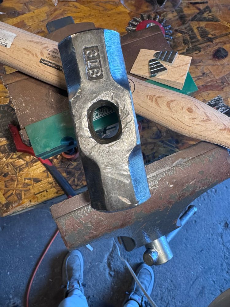 Hammer head and new handle sitting on vice with wood and metal wedges 