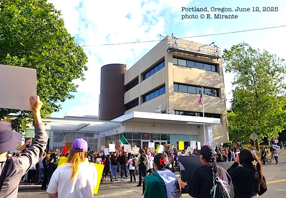 crowd of people face 4 story ICE building in Portland, Oregon
