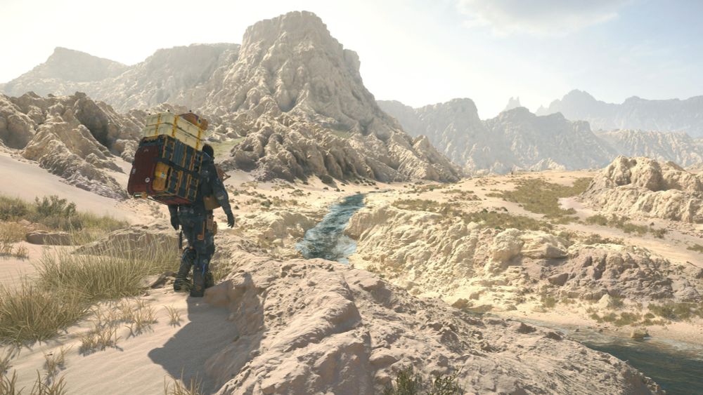 Sam looks out over a shallow stretch of river wending through rough-hewn desert terrain.