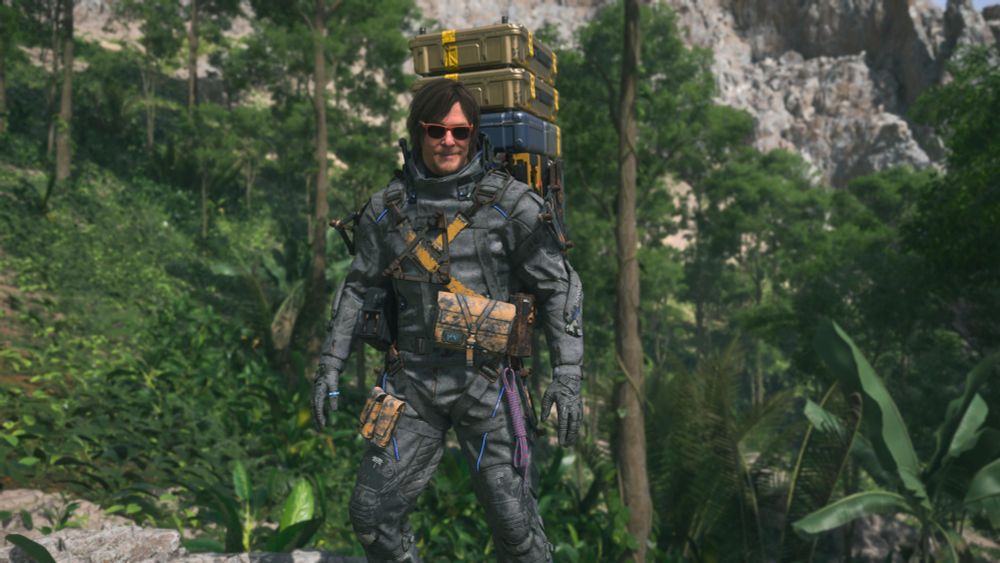 A smiling Sam in jaunty sunglasses stands among verdant foliage in Mexico.