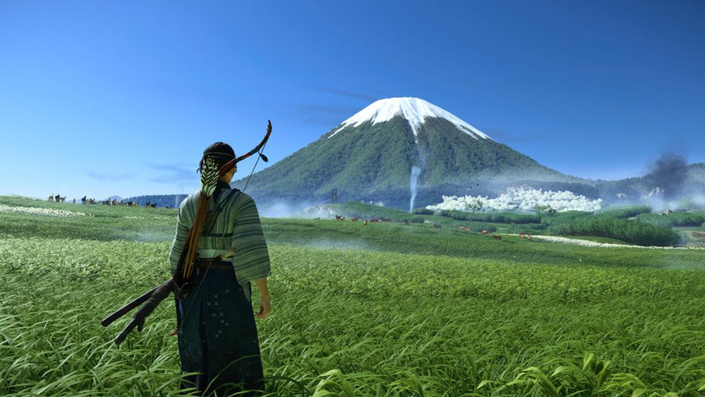 Atsu looks out across vivid green grass at the distant, snow-capped peak of Mount Yōtei.