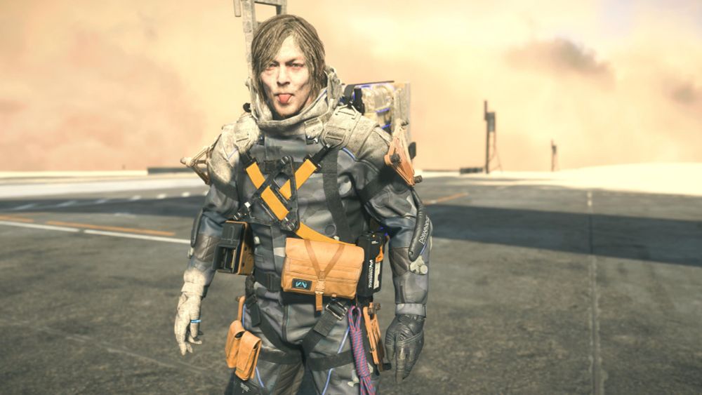 His face and hair caked with sand as a sandstorm churns behind him, Sam sticks his tongue out at the camera.