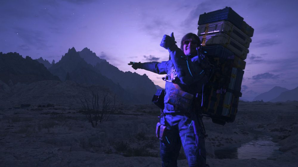 Nightfall in the Mexican desert. Sam grins and gives a thumbs-up as he points to mountains in the near distance.
