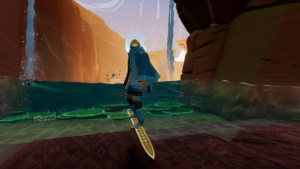 The Wraith looks into the camera, at rest in a patch of shade in a canyon. Two waterfalls appear behind her.