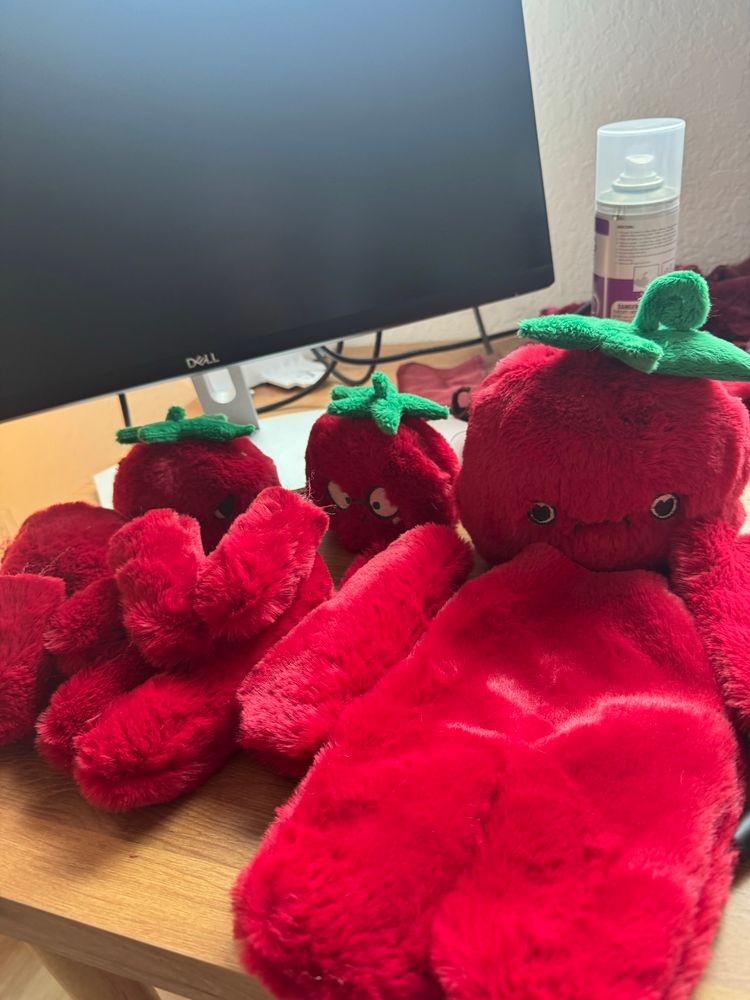 three yet to be assembled tomato plushies chilling in a row on my desk