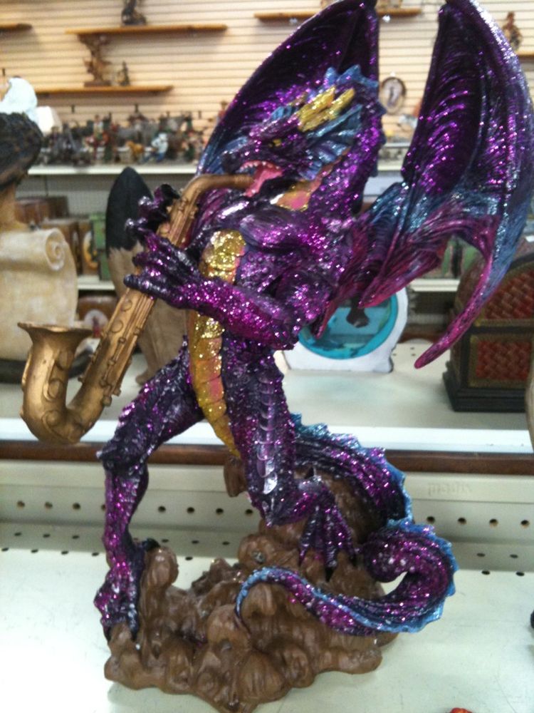 a photograph of a sculpture of a purple sparkly dragon playing the saxophone