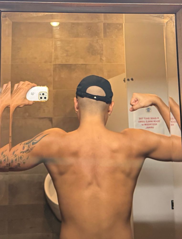 posing for a mirror selfie from behind, showing off back muscles