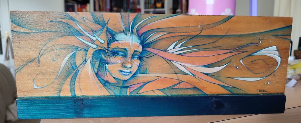 Illustration sur bois représentant un visage de femme aux yeux fermés. Elle est entourée de ligne qui forment des sortes d'arabesques blanches, oranges et rose pâle 