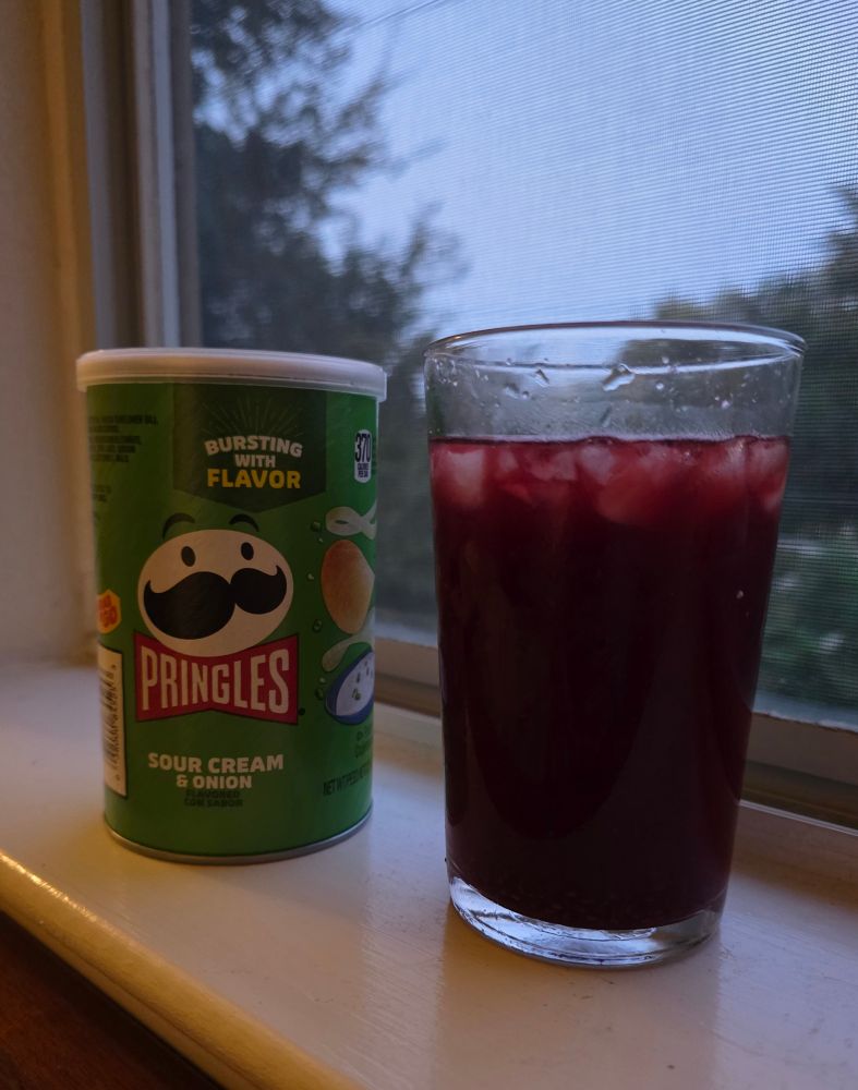 Pringle and a drink looking out a window 