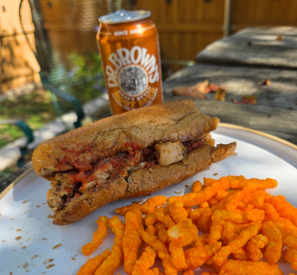 A delicious chicken parm sub on wheat, cheetos  and a root beer on a pick nick table. Only November through February 