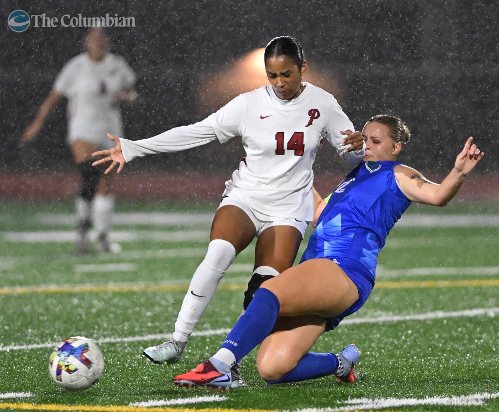 Mountain View senior Nevaeh Irvin, right, slides to kick the ball away from Prairie sophomore Abbigail Bennett (14) on Thursday, Nov. 6, 2025, during Mountain View’s 5-1 win against Prairie in the 3A district championship game at Mountain View High School. (Taylor Balkom/The Columbian)