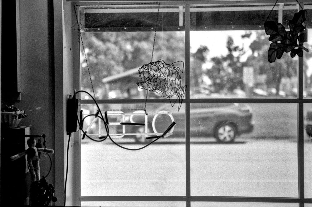 black and white photo out window through "open" sign
