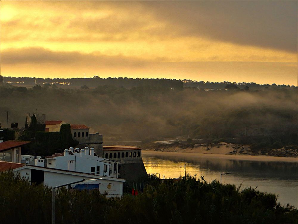 Sunrise with mist + fog moving up the river Mira from the Atlantic with sandy beach on one side + 18th c Fort São Clemente on the other as Pirate protection. Portugal by Sonja Holverson