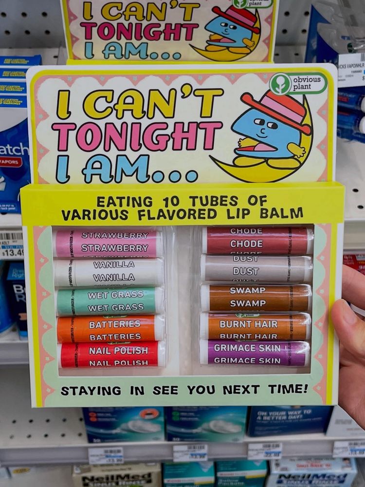 The image displays a novelty product from "Obvious Plant" titled "I CAN'T TONIGHT I AM... EATING 10 TUBES OF VARIOUS FLAVORED LIP BALM". 
This product is a humorous take on lip balm, featuring unusual and unappealing flavors such as "Chode," "Dust," "Swamp," "Burnt Hair," "Grimace Skin," "Wet Grass," "Batteries," and "Nail Polish," alongside more conventional "Strawberry" and "Vanilla".