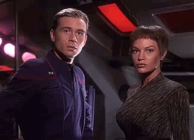 a man and a woman are standing next to each other in a room and looking at each other .