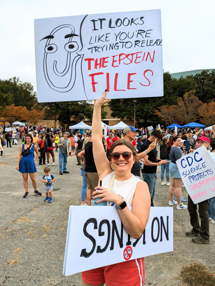 A protester at the no. Kings in Atlanta on October 18th, 2025 holds up a sign with a Windows paperclip that is saying it looks like you're trying to release the Epstein files