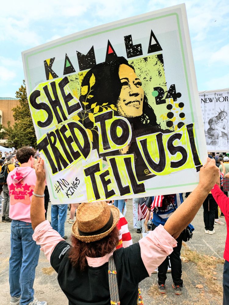 A woman holds up a sign at Atlanta's. No Kings protest that reads. She tried to tell us and shows a picture of Kamala Harris