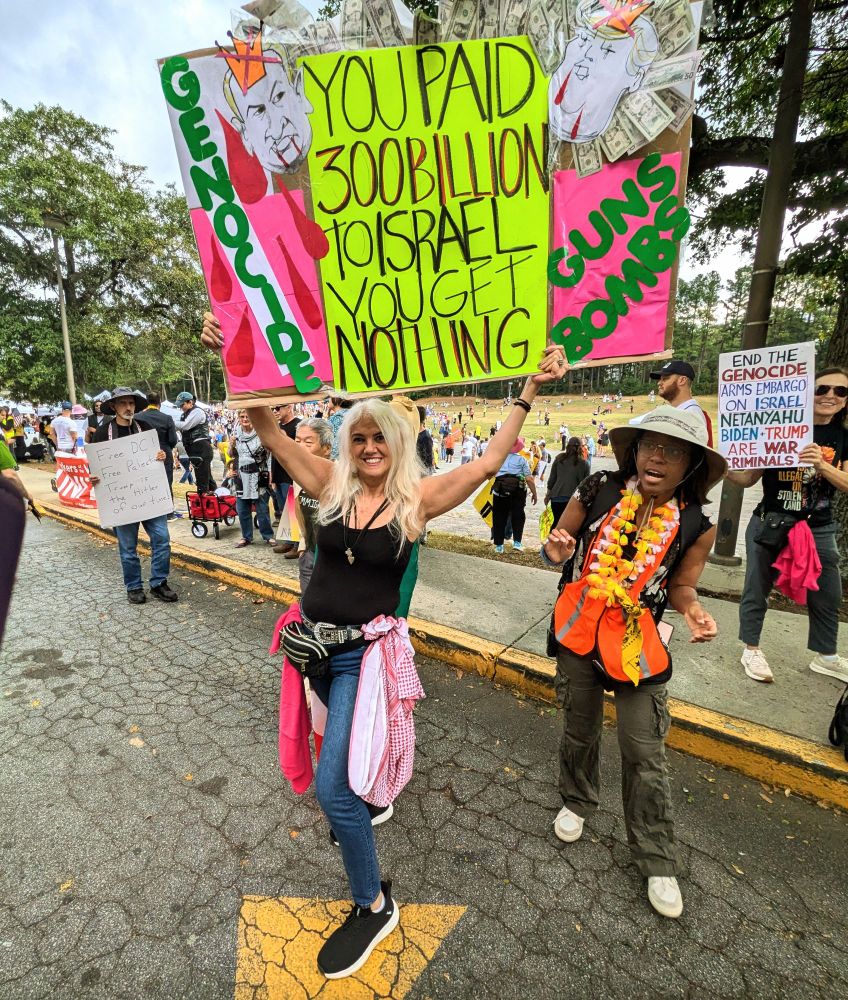 A protester holds up a sign that says you paid $300 billion to Israel and you get nothing at the No Kings protest in Atlanta on October 18th 2025.