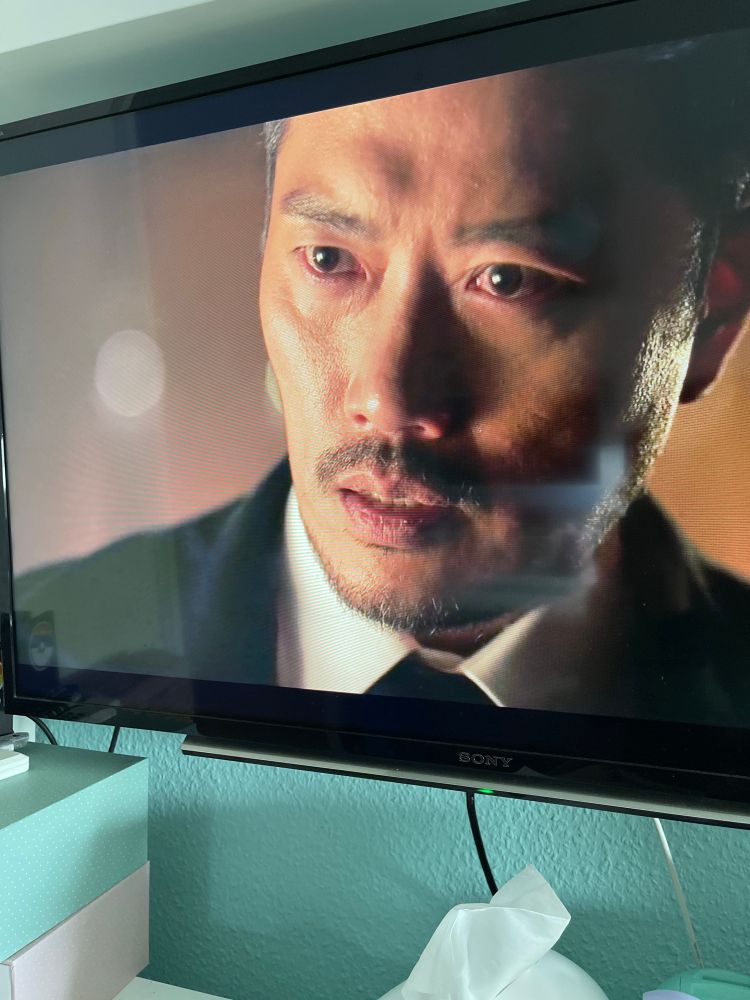 You see the actor Park Hee-Soon he stood in front of the camera. He is wearing a black suit 