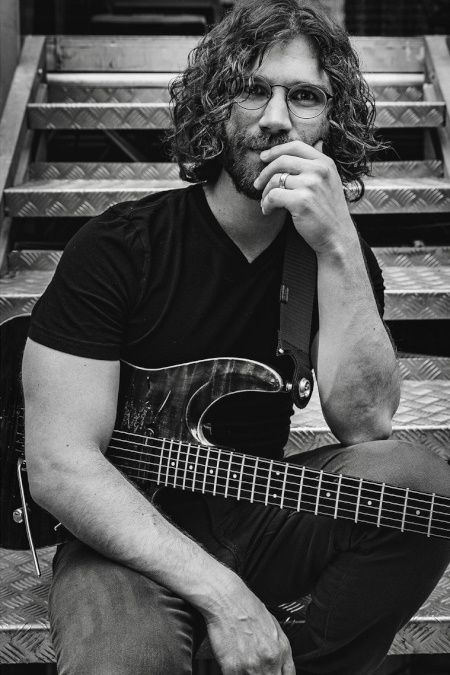 Randy McStine with one of his guitars, sitting on the stairs