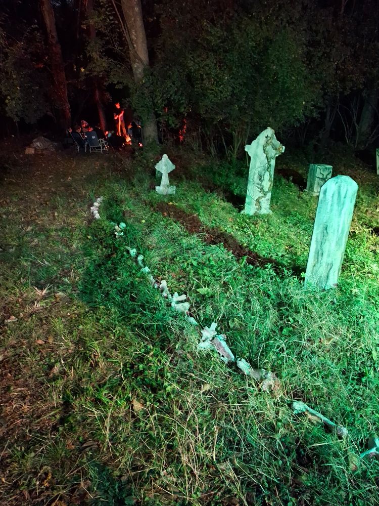 Photo of Spooky decorations including gravestones with a path of bones leading down to a bonfire in the woods