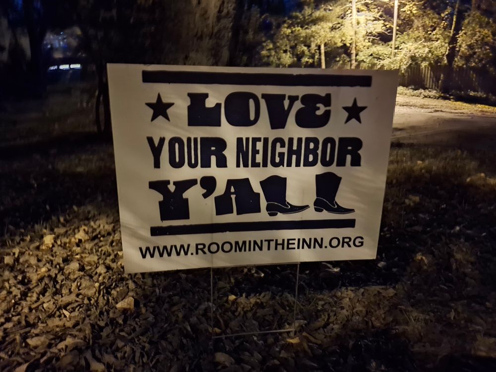 Yard sign which reads,  "Love your neighbor,  y'all- www.roomintheinn.org"