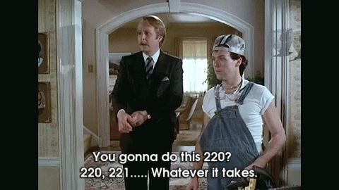 GIF of a scene from the film "Mr. Mom," in which Michael Keaton's character is trying to convince Martin Moll's character of his manliness, branding a chainsaw ready to get to work on renovating the house; Mull asks if he's gonna do this 220, to which Keaton takes a beat to wonder what he meant by that, then responds, "220, 221… Whatever it takes."