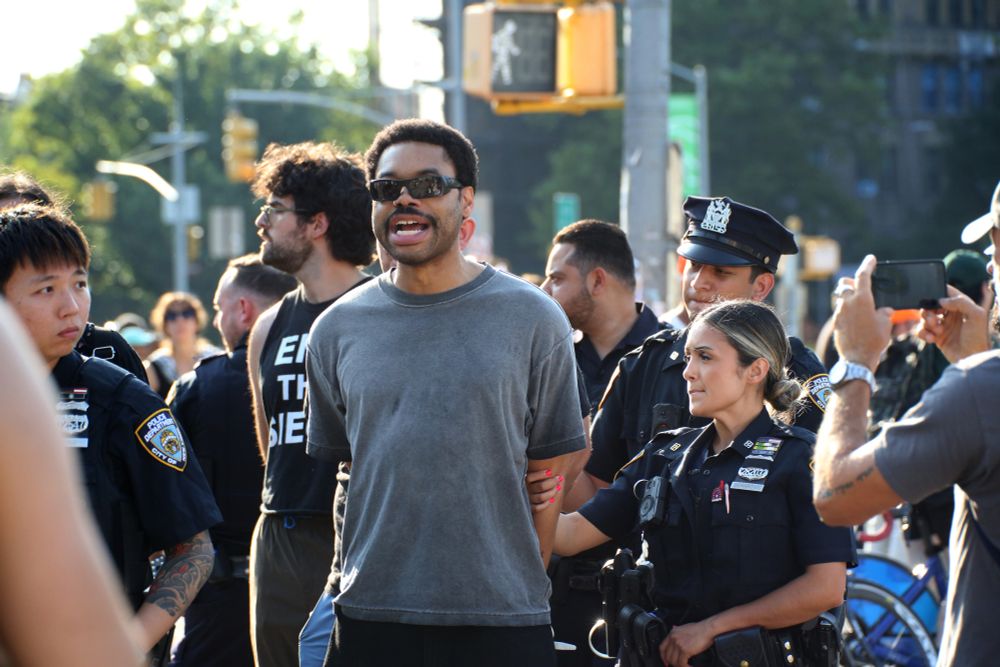 Protester continues chanting as cops lead him towards the camera. His hands are tied behind his back.