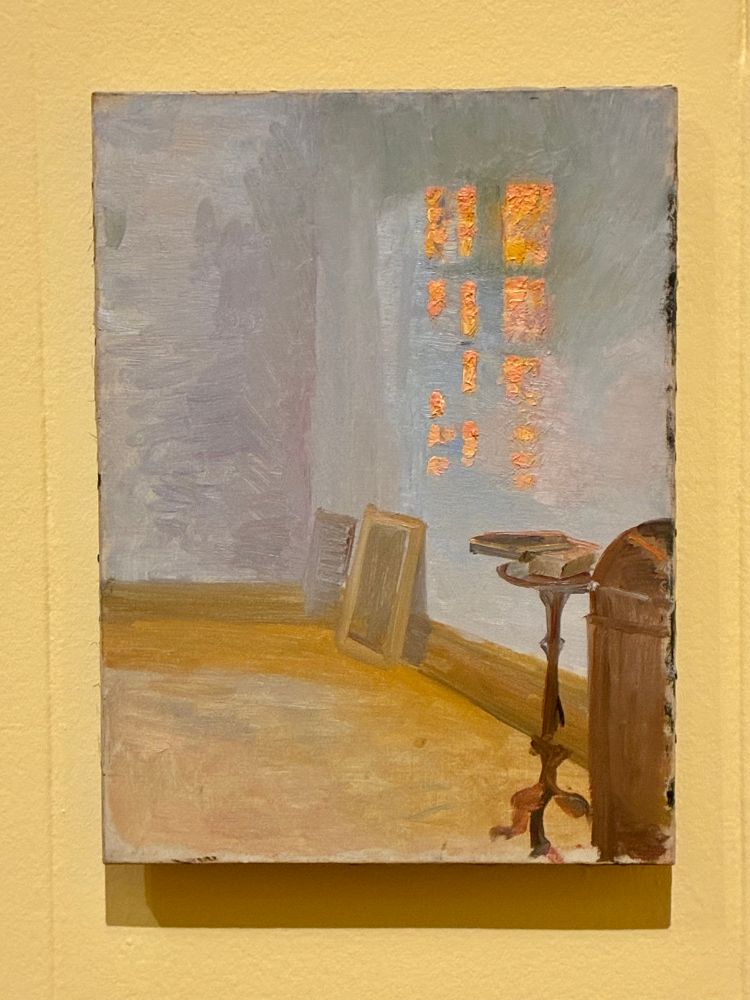 Light on wall in room with side table and picture leaning against a wall 