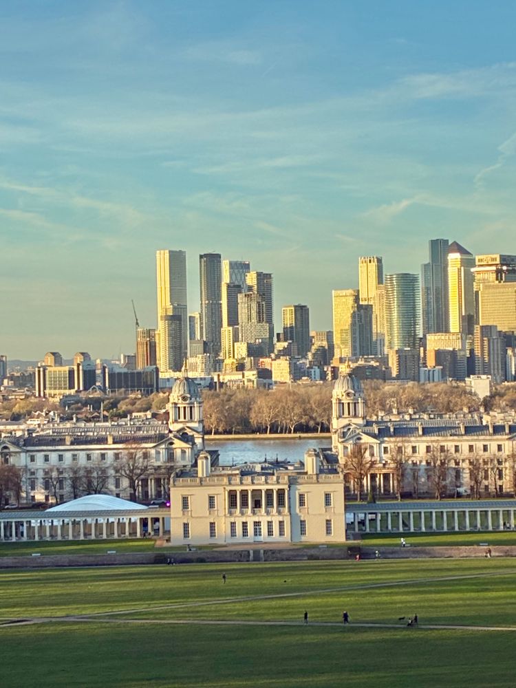 White house with colonnades, park in front, River Thames and high rise office buildings behind, blue sky