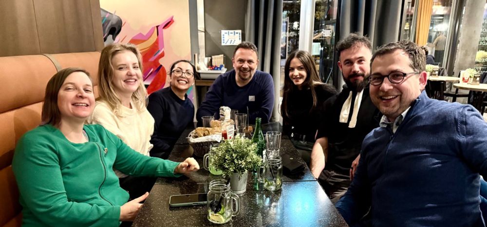 seven people, program committee members, having dinner and smiling