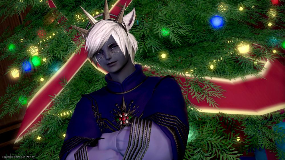 Male Moonkeeper Miqo’te from FFXIV - Aristide Lorin, dressed in a blue and lavender Starlight outfit in front of a bright green holiday tree background, smiling.