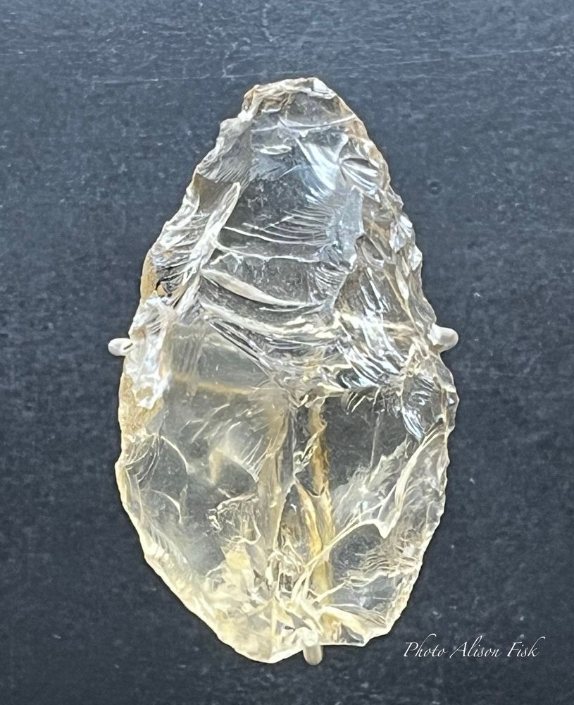 My photo shows a slightly ovoid-shaped tool knapped from rock crystal which has a slighly yellow tinge, mounted for display against a grey background. The tool measures 6 x 3.3 x 1.5 cm. It was recovered from a Mousterian (Neanderthal) level in the Merveilles rockshelter in France during excavations in the 1920s. Six further rock crystal tools were found at the same site.