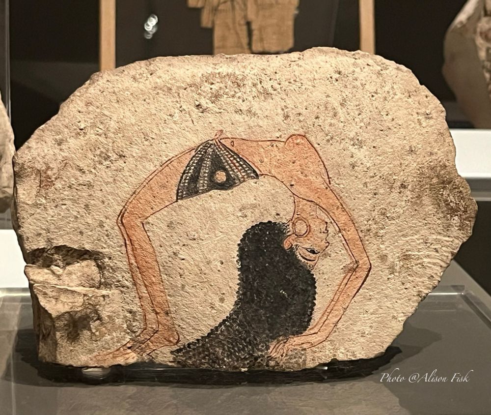 My photo shows a limestone fragment measuring 17 cm x 11.5 cm x 4 cm with a painting of a female dancer shown in profile performing an acrobatic back bend, a so-called ‘crab’ position. The girl has long wavy/crimped black hair which falls down to the ground. She is wearing large gold circular earrings and a black kilt with a decorative red and white pattern which is tied at the front around her hips. 

This limestone fragment comes from the Workers Village of Deir el-Medina which housed the artisans who worked on the royal tombs in the Valley of the Kings. Artists used ostraca (flakes of limestone and broken pottery pieces) as sketch and note pads for practice drawings, sketching, writing poetry etc.etc. Thousands of ostraca have been found at Deir-el Medina.