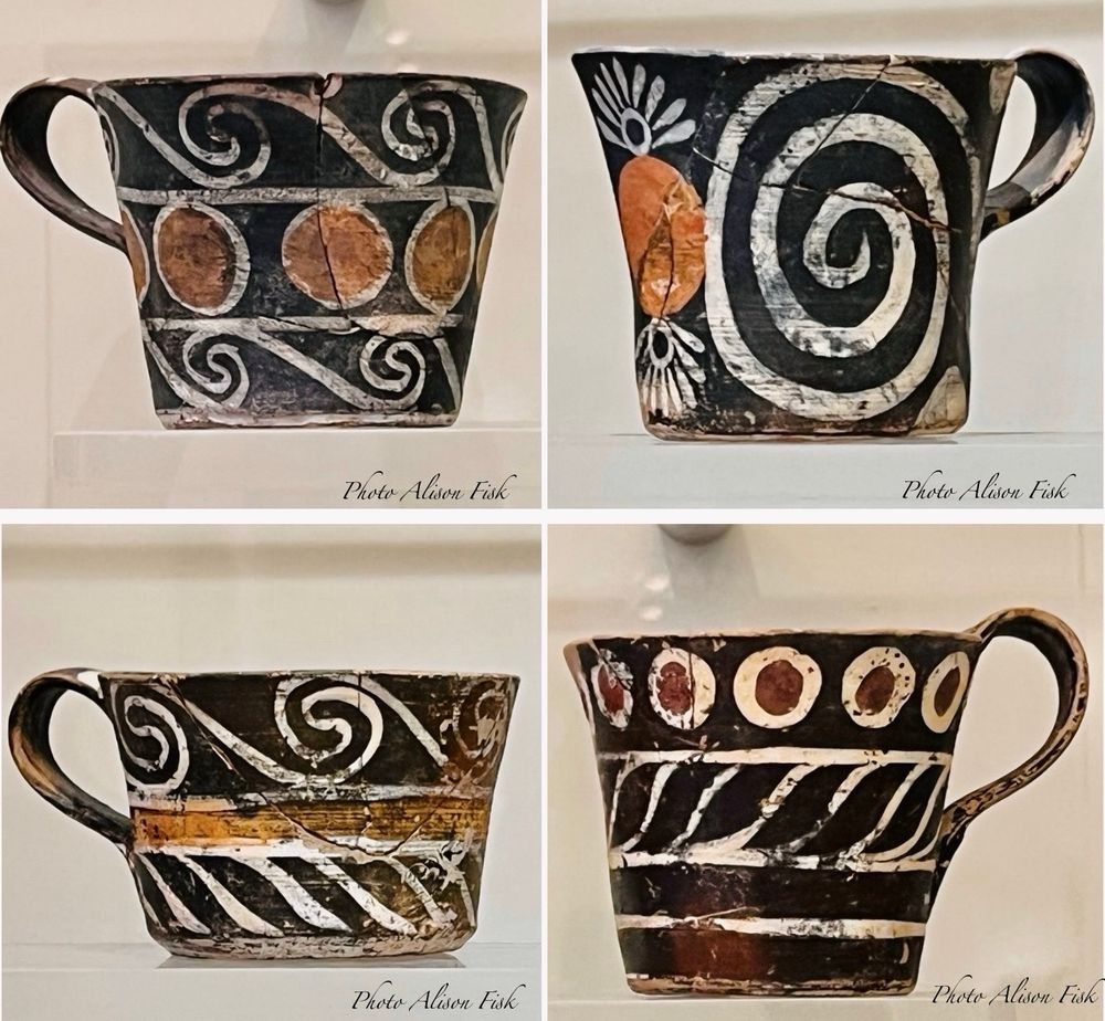 My photo collage shows four cylindrical Minoan cups each with a single handle and each decorated with a different polychrome motif, including white spirals, white whorls, white petals, red spots, orange spots, orange bands, and white bands, all painted on a black background. This type of ornamental Minoan pottery is known as Kamares Ware, named after the Kamares Cave on Mount Ida on Crete where this kind of pottery was first found. Kamares Ware vessels were luxury items produced by palace workshops at Phaistos and Knossos on Crete. These four cups were excavated at Phaistos and dated 1800-1700 BC.