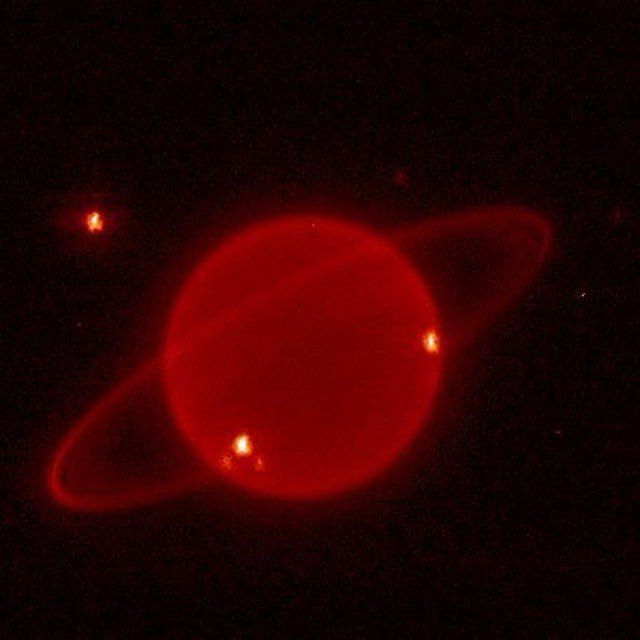 Image of a red Saturn in space with red stars around it 