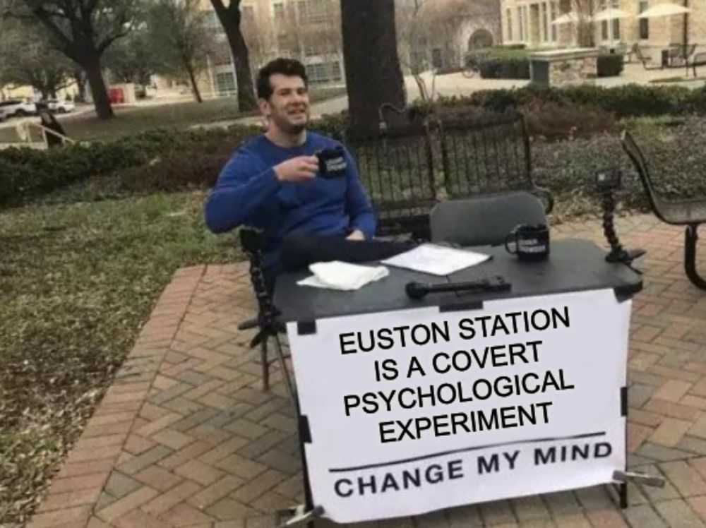 The "change my mind" guy sat in the park with a table. The sign on the front of the table reads "EUSTON STATION IS A COVERT PSYCHOLOGICAL EXPERIMENT. CHANGE MY MIND"