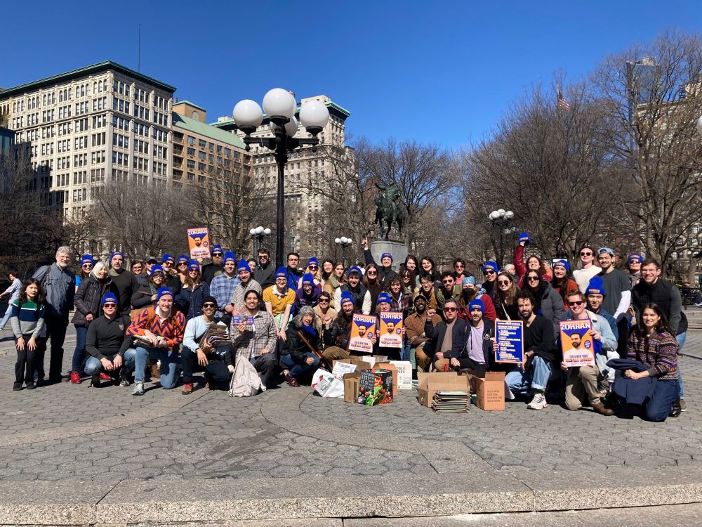 Dozens of volunteers posing together with Zohran for NYC posters in Union Square. 