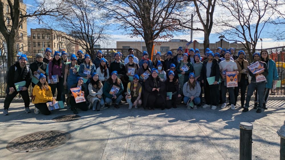 Dozens of volunteers posing together with Zohran for NYC posters.