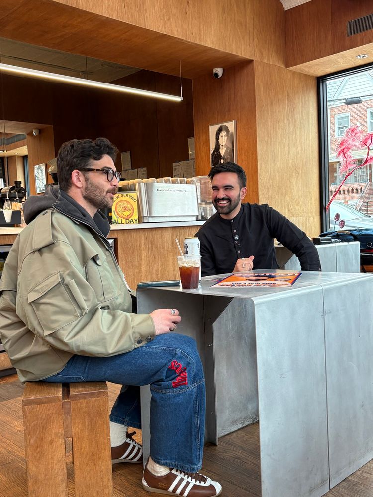 Hasan Piker and Zohran Mamdani sitting in a cafe. 