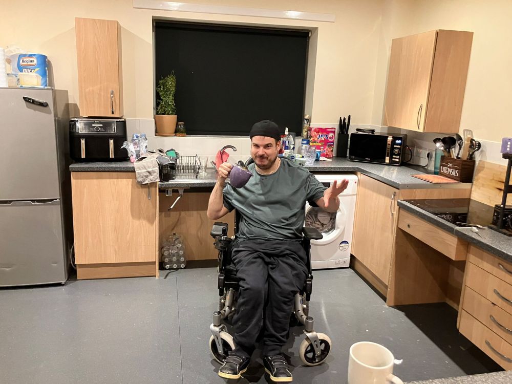 A very handsome man in a wheelchair holding a teapot 