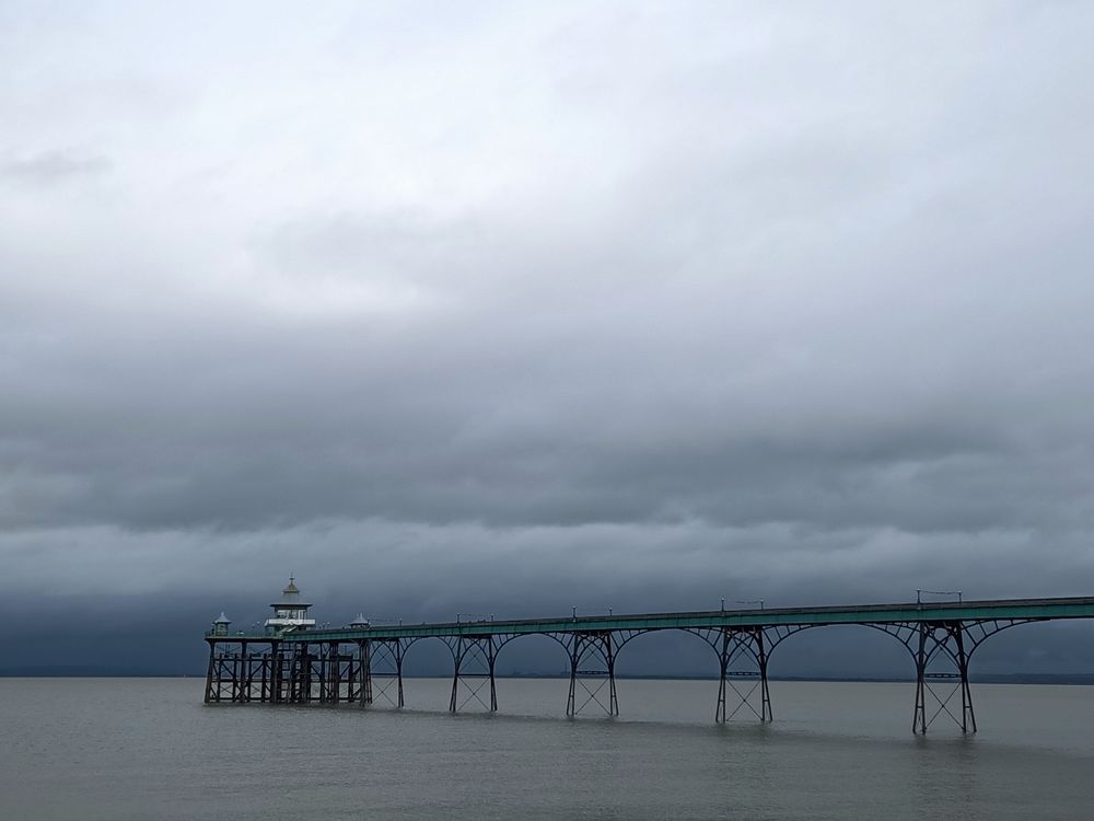 Metallholzkonstruktion, Pier der in den Bristol Channel hineinführt,am Ende auf dem Pier ein Pavillon, Niedrigwasser und grauer Himmel 