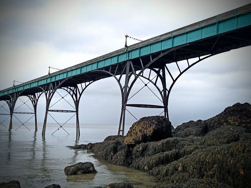 Seitliche Aufnahme des Pier,Felsen im Wasser, Metallkonstruktion,Laufweg mit türkiser Holzverkleidung an der Seite 