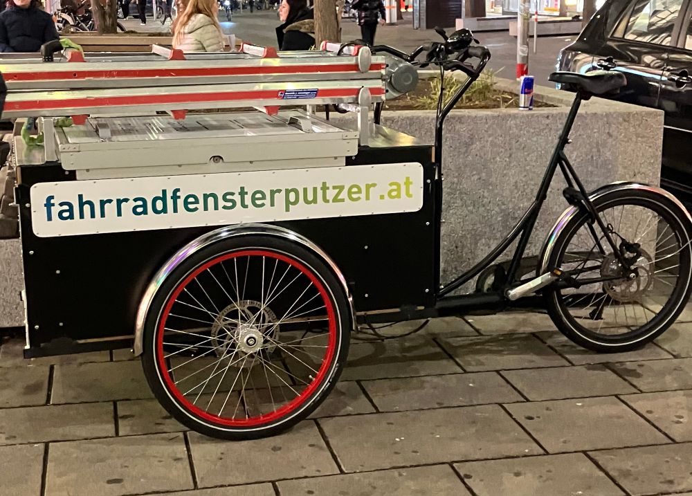 Das Foto zeigt ein schwarzes Lastenrad mit zusammengelegter Leiter und der Aufschrift fahrradfensterputzer.at Foto: VCÖ