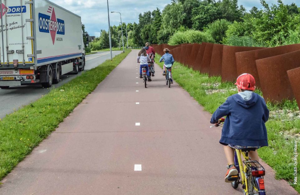 Foto: Dutch Cycling Embassy -  Link Lkw auf Freilandstraßen  - rechts radfahrende Kinder  auf baulich getrennten Radweg